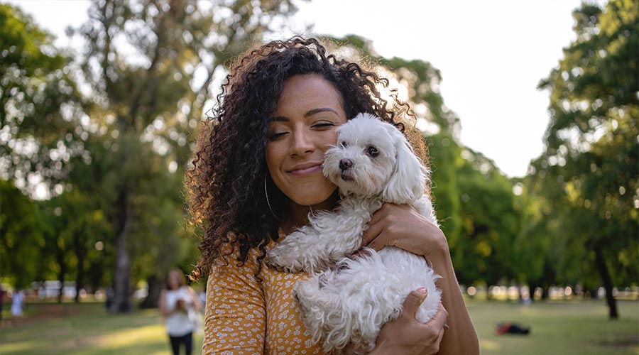 happy woman snuggling small dog